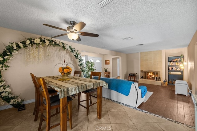44112 Precise St, Lancaster, CA 93536 - tiled dining room featuring a fireplace, a textured ceiling, and a ceiling fan