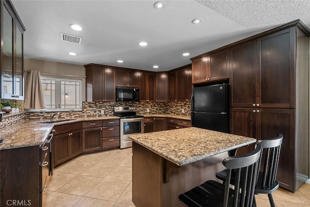 44112 Precise St, Lancaster, CA 93536 - kitchen featuring black appliances, a breakfast bar area, light stone countertops, light tile patterned floors, and tasteful backsplash