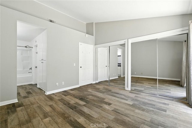 24571 Camden Ct, Laguna Niguel, CA 92677 - unfurnished bedroom with multiple closets, wood finished floors, vaulted ceiling, and ensuite bathroom
