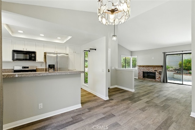 24571 Camden Ct, Laguna Niguel, CA 92677 - kitchen with stainless steel appliances, a chandelier, wood finished floors, white cabinetry, and a tray ceiling