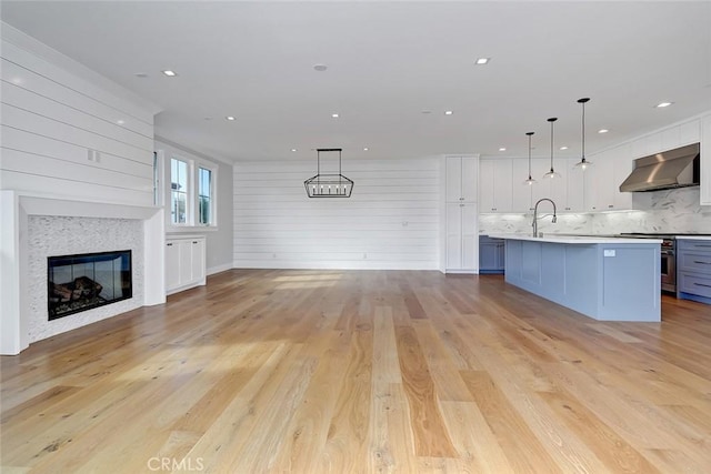 1100 Cypress Ave, Hermosa Beach, CA 90254 - kitchen featuring wall chimney range hood, open floor plan, decorative backsplash, light wood-style floors, and white cabinetry