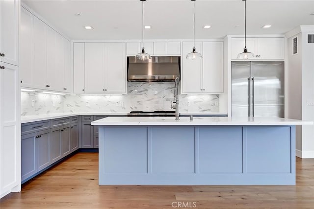 1100 Cypress Ave, Hermosa Beach, CA 90254 - kitchen with wall chimney exhaust hood, stainless steel built in fridge, gray cabinetry, backsplash, and a kitchen island with sink
