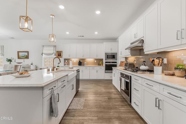 566 Purple Sage Ln, Simi Valley, CA 93065 - kitchen with stainless steel appliances, under cabinet range hood, tasteful backsplash, white cabinetry, and wood finished floors