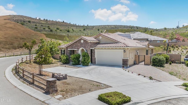 566 Purple Sage Ln, Simi Valley, CA 93065 - mediterranean / spanish home with a gate, a tile roof, an attached garage, driveway, and stucco siding