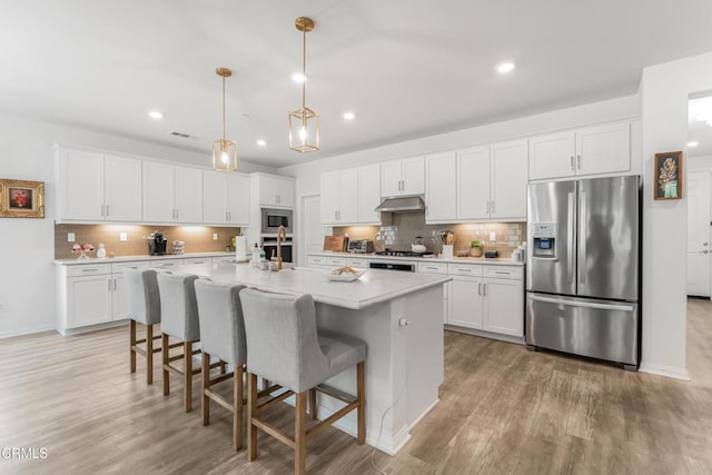 566 Purple Sage Ln, Simi Valley, CA 93065 - kitchen featuring appliances with stainless steel finishes, under cabinet range hood, backsplash, light wood-type flooring, and white cabinetry