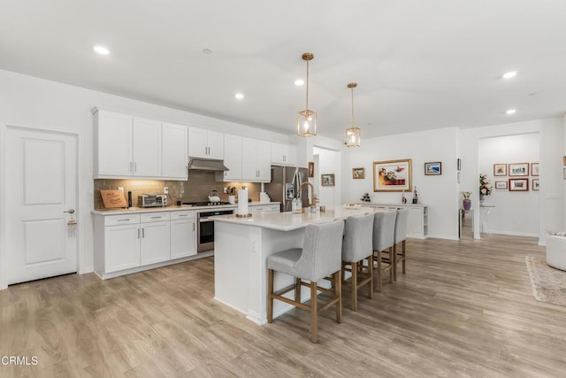 566 Purple Sage Ln, Simi Valley, CA 93065 - kitchen with stainless steel appliances, light countertops, a kitchen bar, light wood-style floors, and recessed lighting