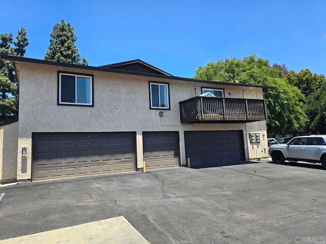 10135 Peaceful Ct, Santee, CA 92071 - view of front of home with an attached garage, a balcony, stucco siding, and asphalt driveway