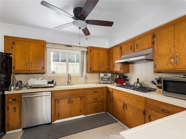 512 Lomita St, El Segundo, CA 90245 - kitchen with appliances with stainless steel finishes, under cabinet range hood, brown cabinetry, a ceiling fan, and light countertops