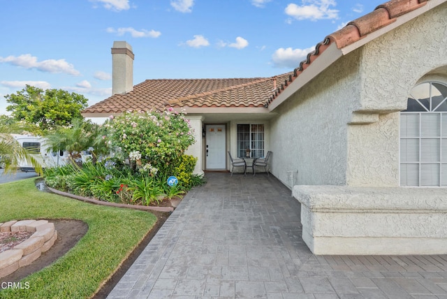 1306 Bluejay St, Fillmore, CA 93015 - property entrance featuring stucco siding, a tiled roof, and a chimney