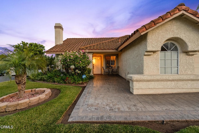 1306 Bluejay St, Fillmore, CA 93015 - view of front facade with stucco siding, a tiled roof, a chimney, and a yard