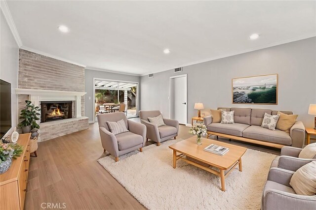 1141 N Palm St, La Habra, CA 90631 - living room with light wood-style flooring, a brick fireplace, crown molding, and recessed lighting
