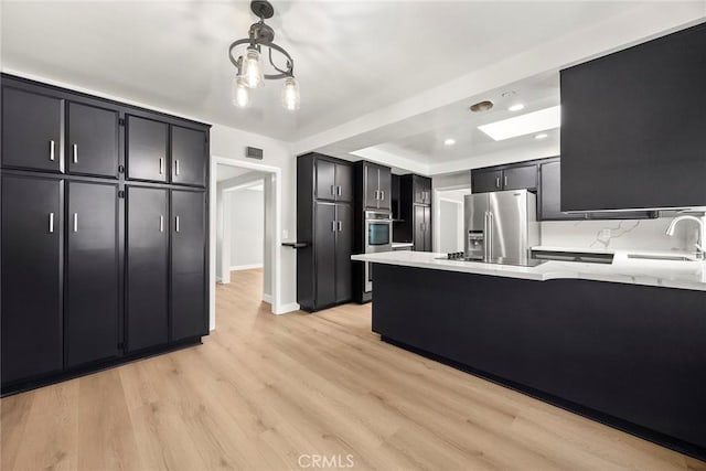 1141 N Palm St, La Habra, CA 90631 - kitchen with stainless steel appliances, a peninsula, light wood finished floors, dark cabinetry, and recessed lighting