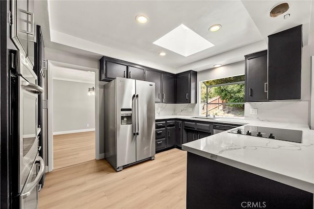 1141 N Palm St, La Habra, CA 90631 - kitchen with appliances with stainless steel finishes, a skylight, light wood-style floors, tasteful backsplash, and recessed lighting