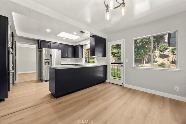 1141 N Palm St, La Habra, CA 90631 - kitchen featuring stainless steel fridge with ice dispenser, dark cabinetry, light countertops, light wood-style floors, and a peninsula