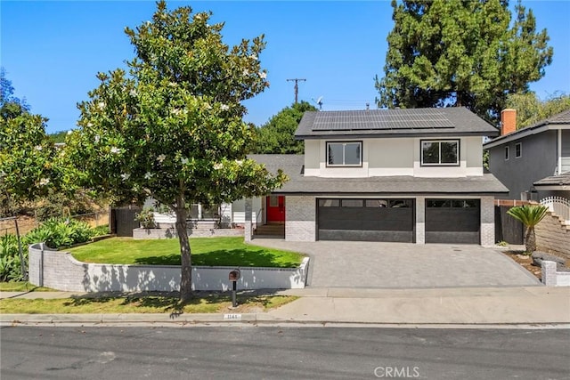 1141 N Palm St, La Habra, CA 90631 - view of front of house with driveway, an attached garage, roof mounted solar panels, brick siding, and stucco siding