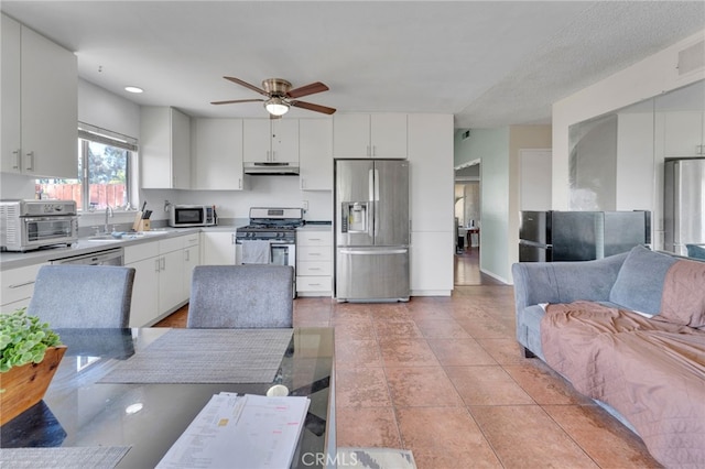 1926 E 7th St, Ontario, CA 91764 - kitchen with appliances with stainless steel finishes, under cabinet range hood, open floor plan, a ceiling fan, and white cabinetry
