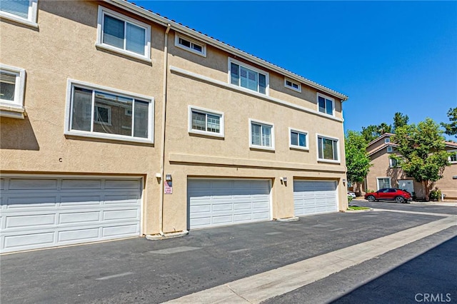 25748 Perlman Pl Unit B, Stevenson Ranch, CA 91381 - view of front facade with stucco siding and a garage