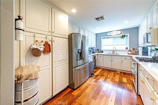 25748 Perlman Pl Unit B, Stevenson Ranch, CA 91381 - kitchen with stainless steel appliances, light wood-style flooring, light countertops, white cabinets, and recessed lighting