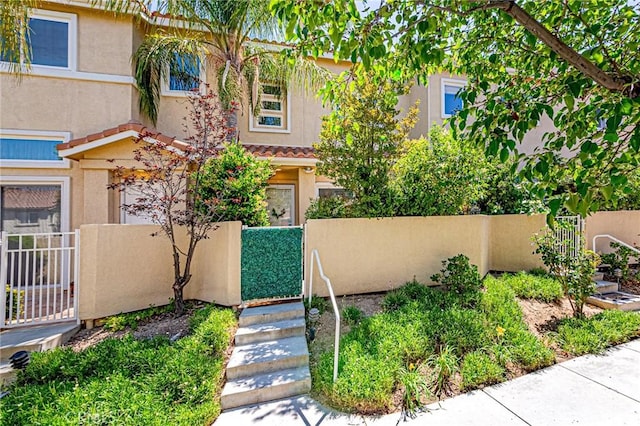 25748 Perlman Pl Unit B, Stevenson Ranch, CA 91381 - view of front facade featuring a fenced front yard, stucco siding, a tiled roof, and a gate