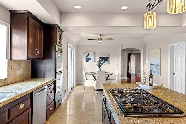 870 Avenida Acapulco, San Clemente, CA 92672 - kitchen with appliances with stainless steel finishes, arched walkways, dark brown cabinetry, a ceiling fan, and light stone counters