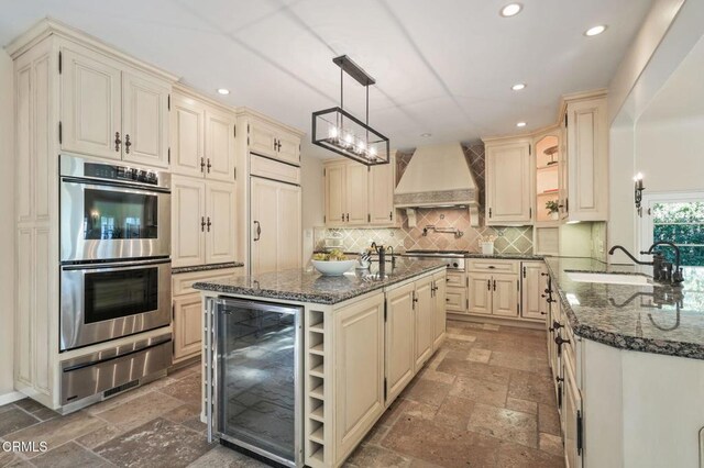 980 El Campo Dr, Pasadena, CA 91107 - kitchen featuring appliances with stainless steel finishes, wine cooler, premium range hood, cream cabinets, and recessed lighting