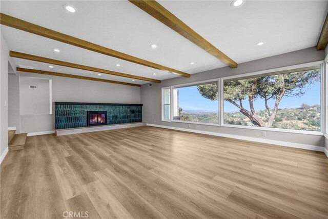 247 El Cielo Ln, Bradbury, CA 91008 - unfurnished living room featuring beamed ceiling, recessed lighting, light wood-style floors, and a glass covered fireplace