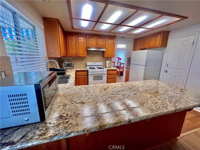 18725 Dallas Ave, Riverside, CA 92508 - kitchen featuring white appliances, under cabinet range hood, wood finished floors, a peninsula, and brown cabinetry