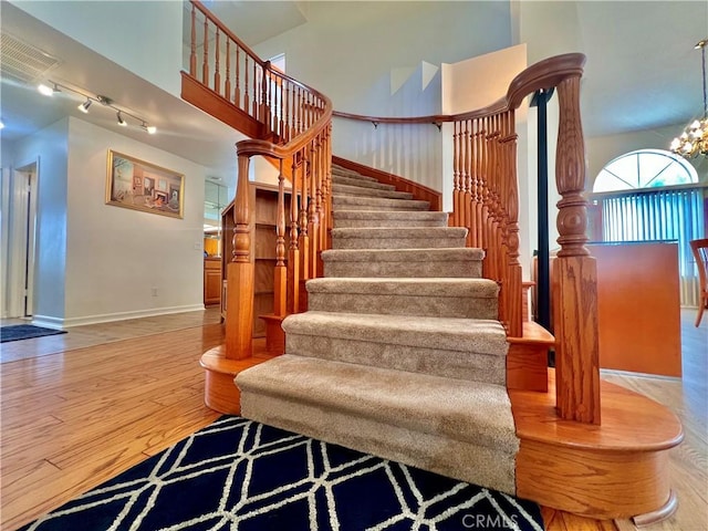 18725 Dallas Ave, Riverside, CA 92508 - stairway with rail lighting, wood finished floors, a high ceiling, and a chandelier