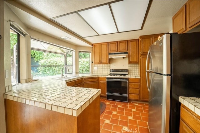 3 Bonanza Ct, Pomona, CA 91766 - kitchen featuring freestanding refrigerator, white range oven, under cabinet range hood, tile countertops, and backsplash