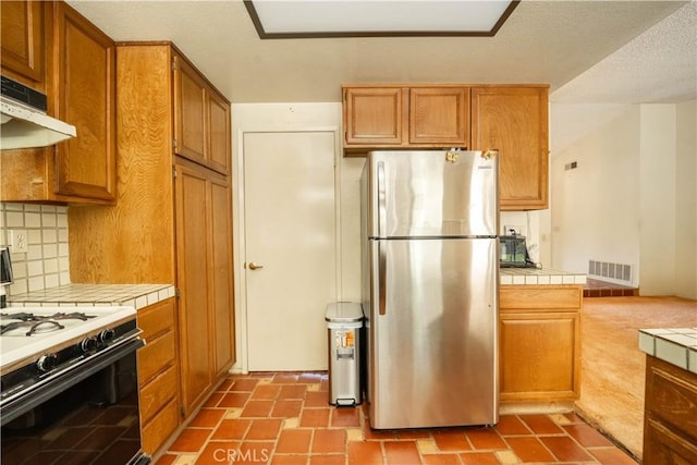 3 Bonanza Ct, Pomona, CA 91766 - kitchen with freestanding refrigerator, tile counters, range with gas cooktop, decorative backsplash, and brown cabinets