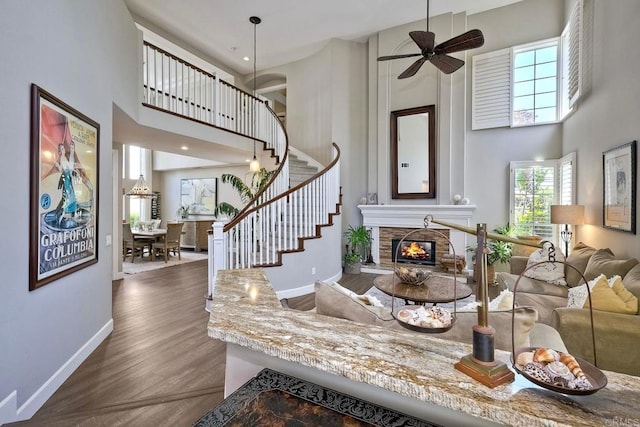1709 Blackbird Cir, Carlsbad, CA 92011 - living room with a high ceiling, a stone fireplace, ceiling fan, stairway, and wood finished floors