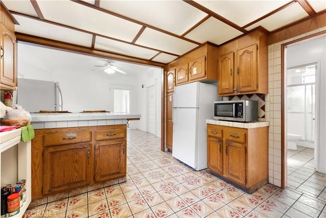 2005 Magnolia Ave, Los Angeles, CA 90007 - kitchen with stainless steel microwave, freestanding refrigerator, tile countertops, and ceiling fan