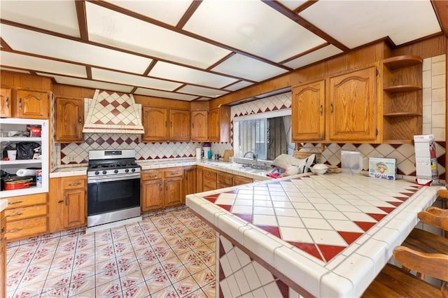 2005 Magnolia Ave, Los Angeles, CA 90007 - kitchen featuring stainless steel gas stove, tile countertops, custom exhaust hood, a peninsula, and open shelves