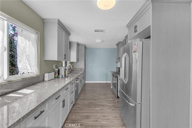 74417 Maricopa Dr Unit 29, Palms, CA 92277 - kitchen featuring appliances with stainless steel finishes, light wood-type flooring, light stone countertops, and gray cabinets