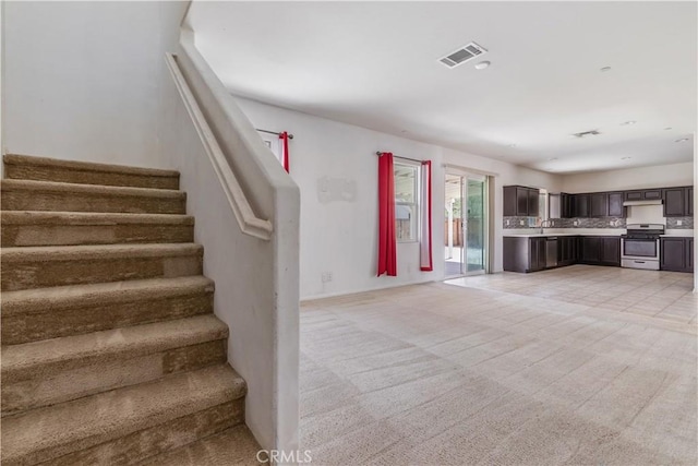 3720 Mount Whitney Ave, Rosamond, CA 93560 - unfurnished living room featuring stairs and light colored carpet
