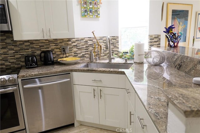 8482 Via Sonoma Unit 18, La Jolla, CA 92037 - kitchen featuring appliances with stainless steel finishes, white cabinets, decorative backsplash, and stone countertops