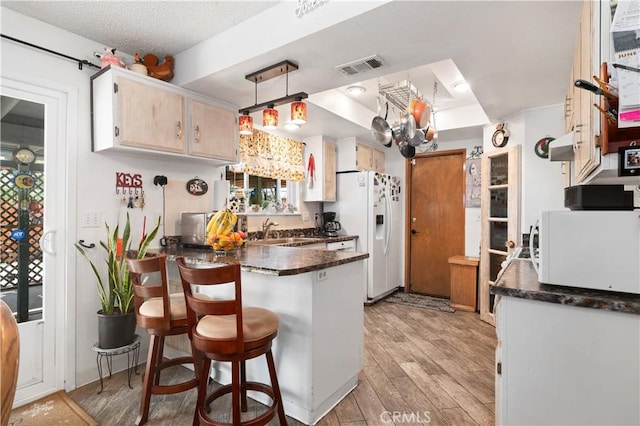 14551 Jelan Ave, Apple Valley, CA 92307 - kitchen with white appliances, a peninsula, dark countertops, light wood-type flooring, and a breakfast bar