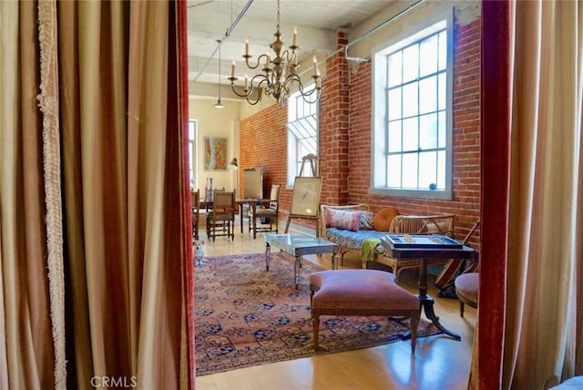 207 Broadway E Unit 302, Long Beach, CA 90802 - sitting room featuring a towering ceiling, brick wall, a chandelier, and wood finished floors