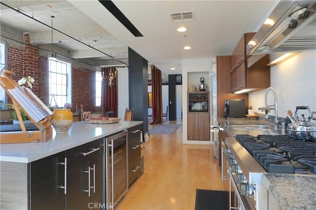207 Broadway E Unit 302, Long Beach, CA 90802 - kitchen with beverage cooler, island range hood, light countertops, light wood-type flooring, and dark cabinetry
