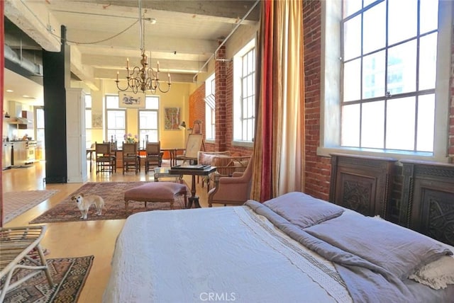 207 Broadway E Unit 302, Long Beach, CA 90802 - bedroom featuring a chandelier, wood finished floors, beam ceiling, a high ceiling, and brick wall