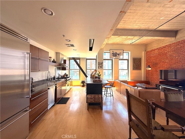 207 Broadway E Unit 302, Long Beach, CA 90802 - kitchen with stainless steel appliances, dark countertops, wall chimney exhaust hood, light wood-type flooring, and brick wall