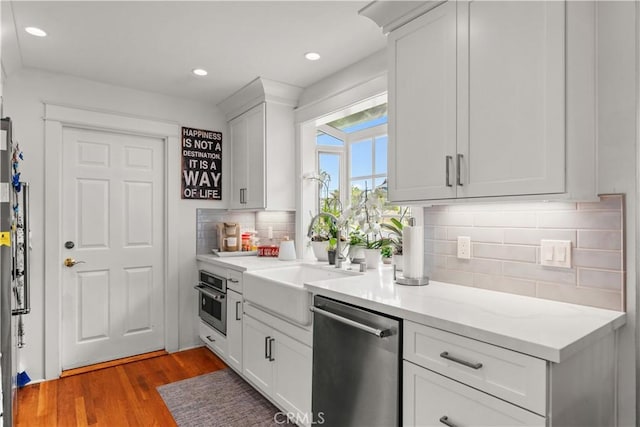 1050 Marvista Ave, Seal Beach, CA 90740 - kitchen with appliances with stainless steel finishes, wood finished floors, decorative backsplash, light countertops, and white cabinets