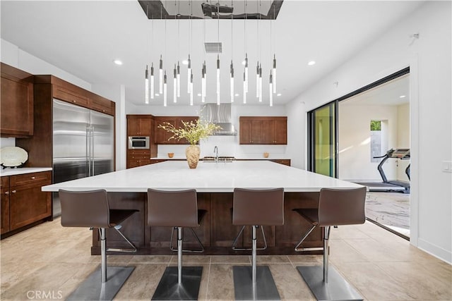 127 Interstellar, Irvine, CA 92618 - kitchen with built in fridge, wall chimney range hood, light countertops, a large island with sink, and a breakfast bar
