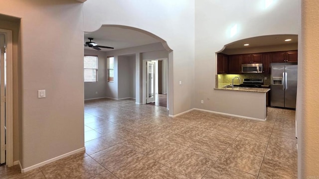 4148 Karst Rd, Carlsbad, CA 92010 - kitchen featuring appliances with stainless steel finishes, arched walkways, a ceiling fan, decorative backsplash, and dark brown cabinetry