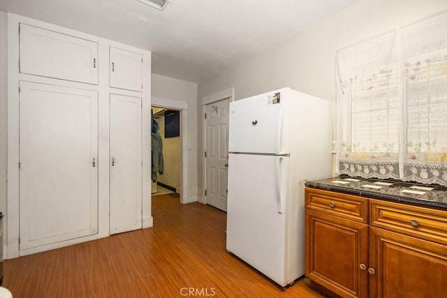 1085 N Arrowhead Ave, San Bernardino, CA 92410 - kitchen with freestanding refrigerator, dark countertops, light wood finished floors, and brown cabinets