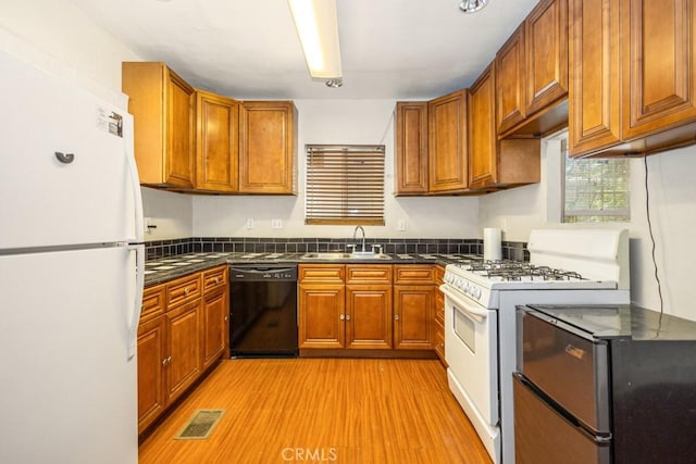 1085 N Arrowhead Ave, San Bernardino, CA 92410 - kitchen featuring white appliances, dark countertops, brown cabinetry, and light wood-style floors