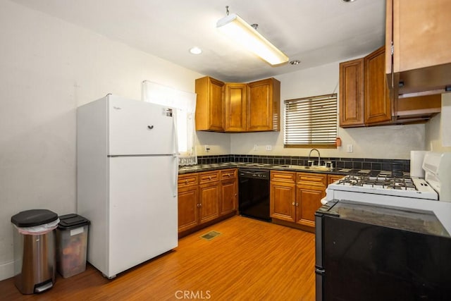 1085 N Arrowhead Ave, San Bernardino, CA 92410 - kitchen with freestanding refrigerator, black dishwasher, dark countertops, brown cabinets, and light wood-type flooring