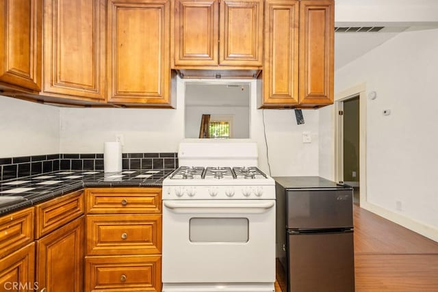 1085 N Arrowhead Ave, San Bernardino, CA 92410 - kitchen with white gas range oven, freestanding refrigerator, dark countertops, and brown cabinets