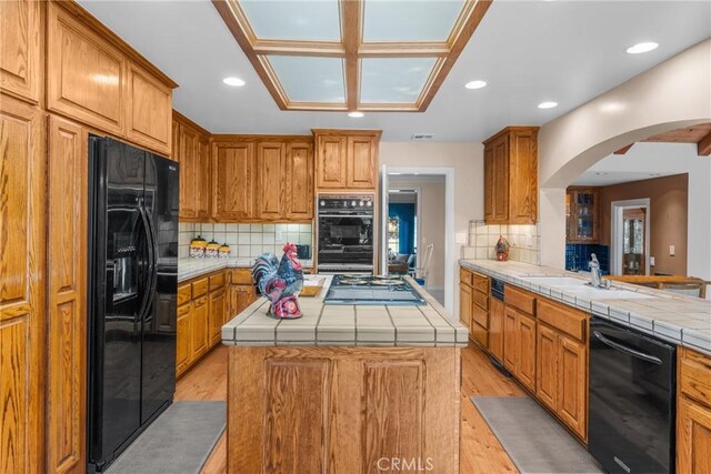 530 Bradbury Rd, Monrovia, CA 91016 - kitchen featuring black appliances, tile countertops, arched walkways, a center island, and recessed lighting