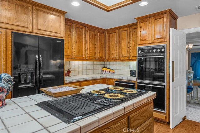 530 Bradbury Rd, Monrovia, CA 91016 - kitchen with black appliances, tile counters, recessed lighting, tasteful backsplash, and light wood-style flooring